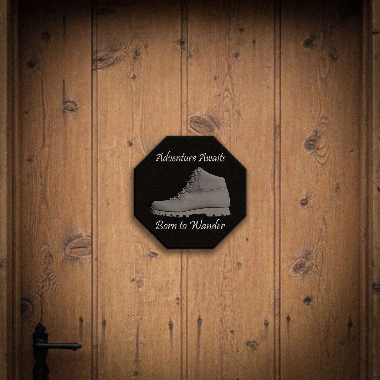 Octagonal sign with hiking boot graphic and text 'Adventure Awaits, Born to Wander' on a wooden door.