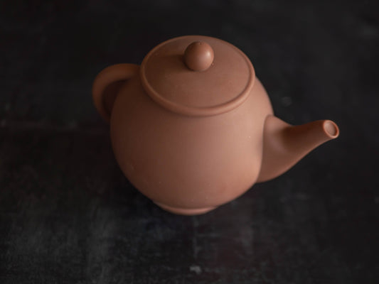 A chocolate teapot made from Belgian chocolate, viewed from a slightly elevated angle against a dark background.