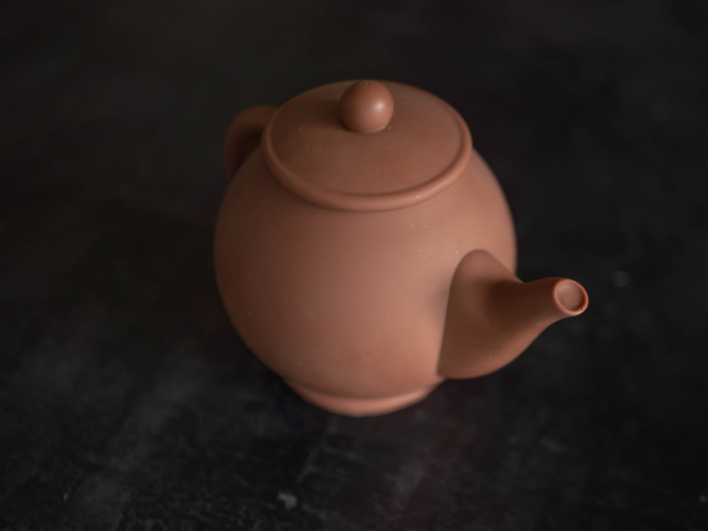 A chocolate teapot made from Belgian chocolate, viewed from a slightly elevated angle against a dark background