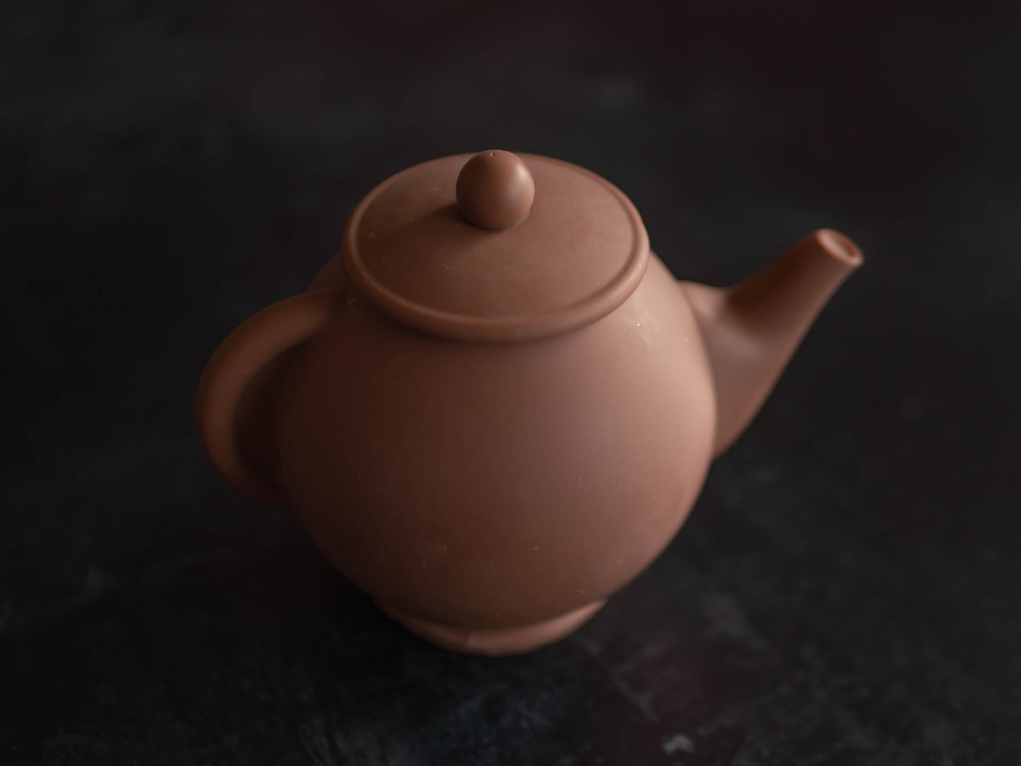 A chocolate teapot made from Belgian chocolate, viewed from a slightly elevated angle against a dark background