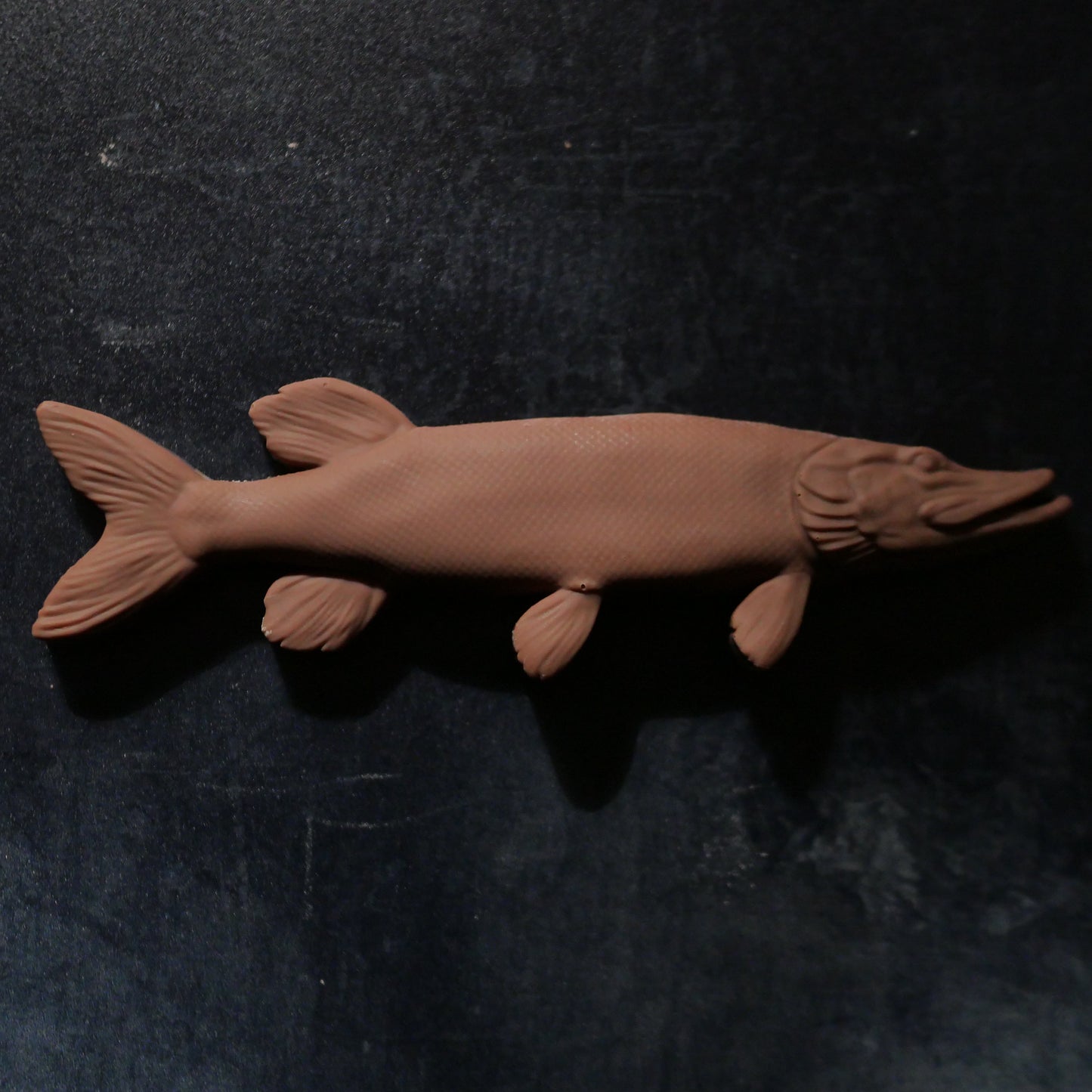 A pike fish-shaped Belgian milk chocolate bar on a dark background.
