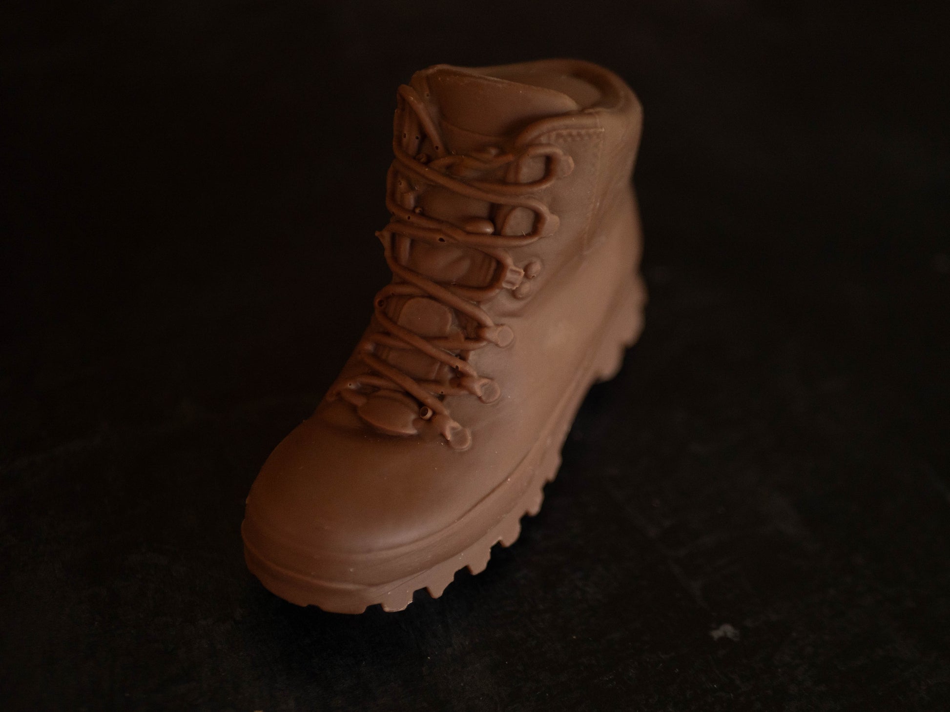 3D chocolate walking boot on a black background.