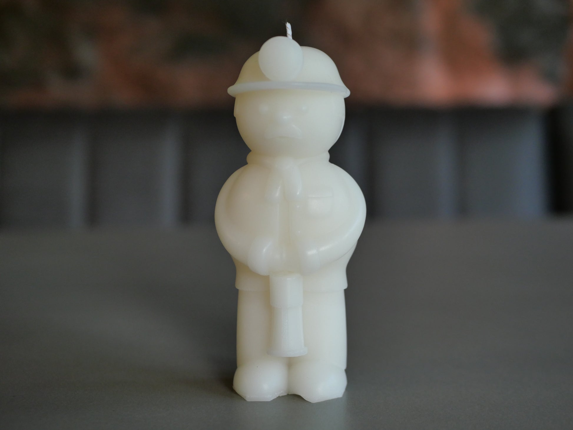 White candle shaped like a miner with a hat on a gray surface