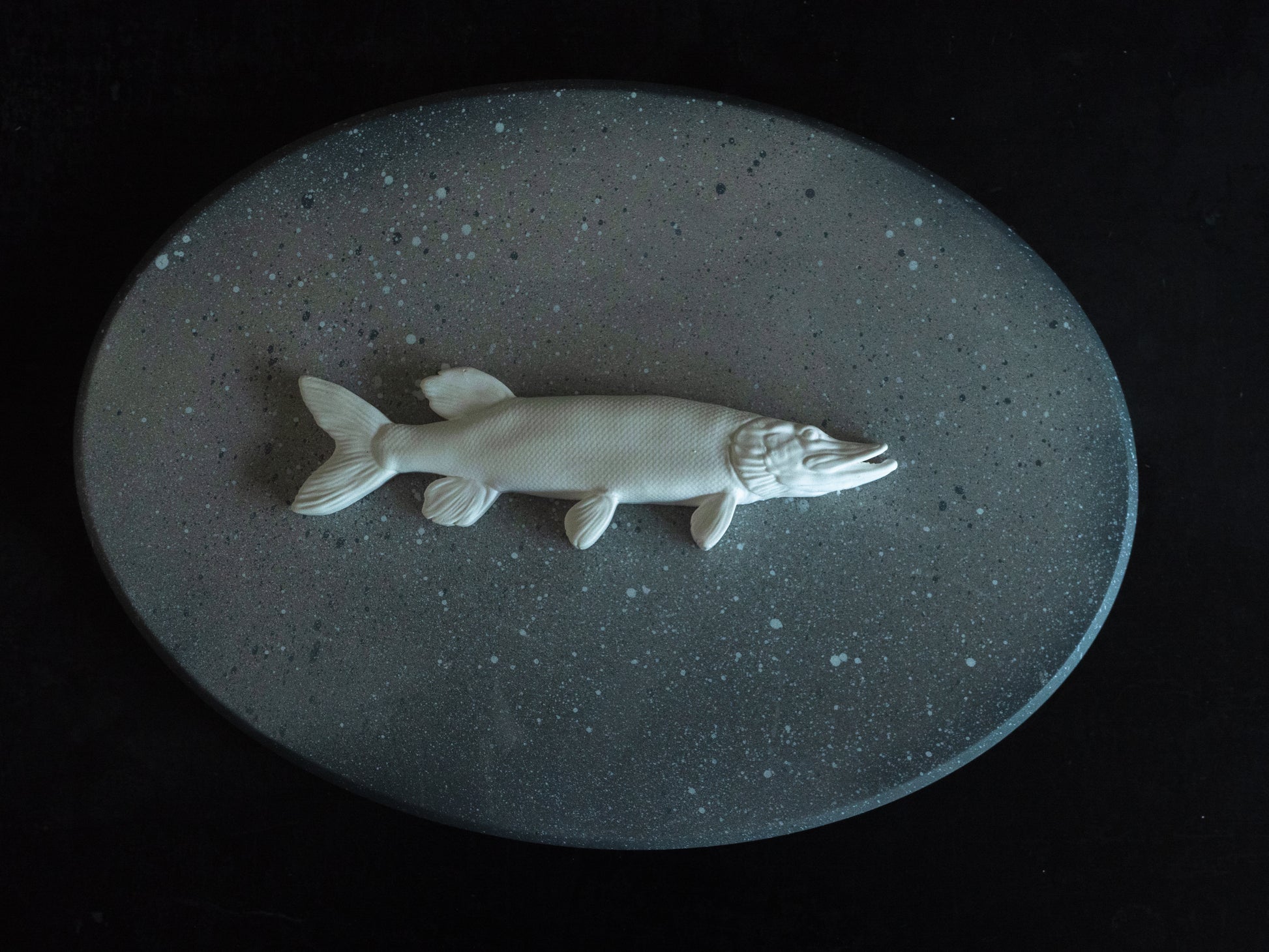 White Pike fish figurine on a grey oval stone