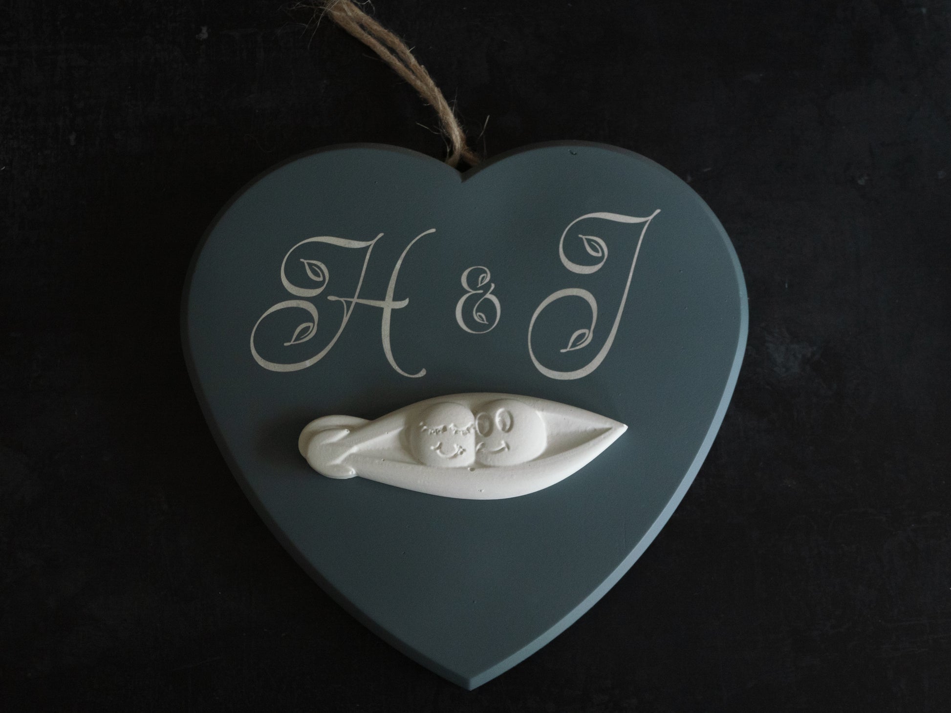 Heart-shaped decoration with 'H & J' initials and two peas in a pod figurine