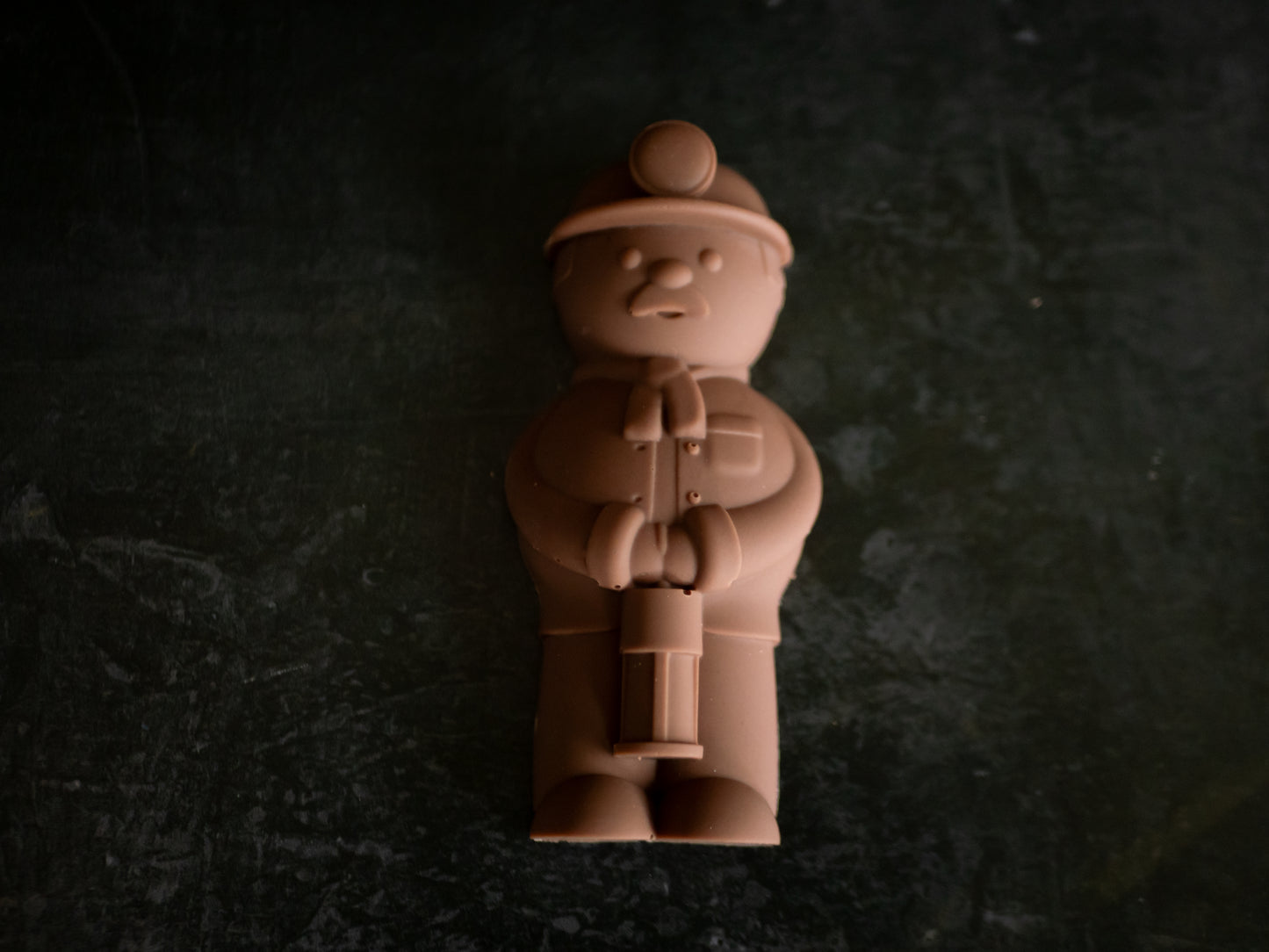 Chocolate figurine of a welsh miner with a hat on a dark textured background