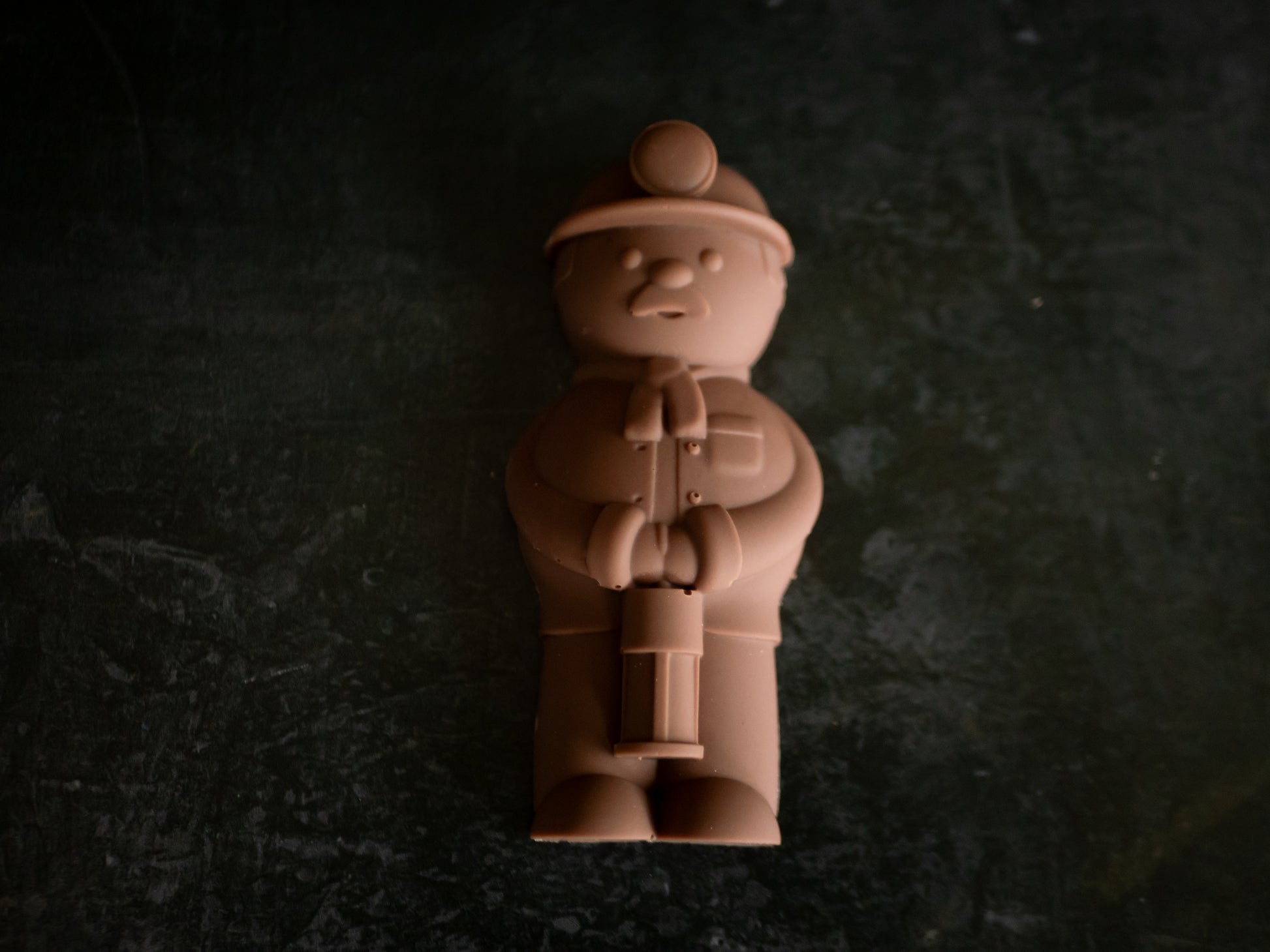 Chocolate figurine of a welsh miner with a hat on a dark textured background