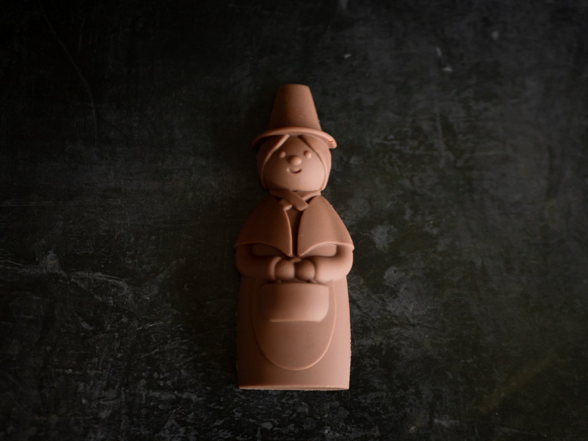 Chocolate figurine of a welsh lady wearing a hat on a dark background
