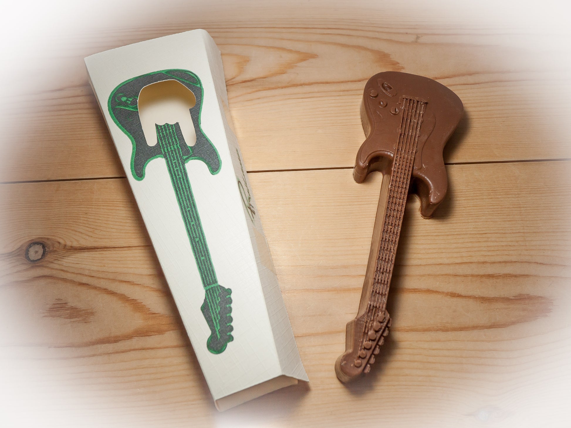 An edible chocolate guitar displayed next to a gift box.