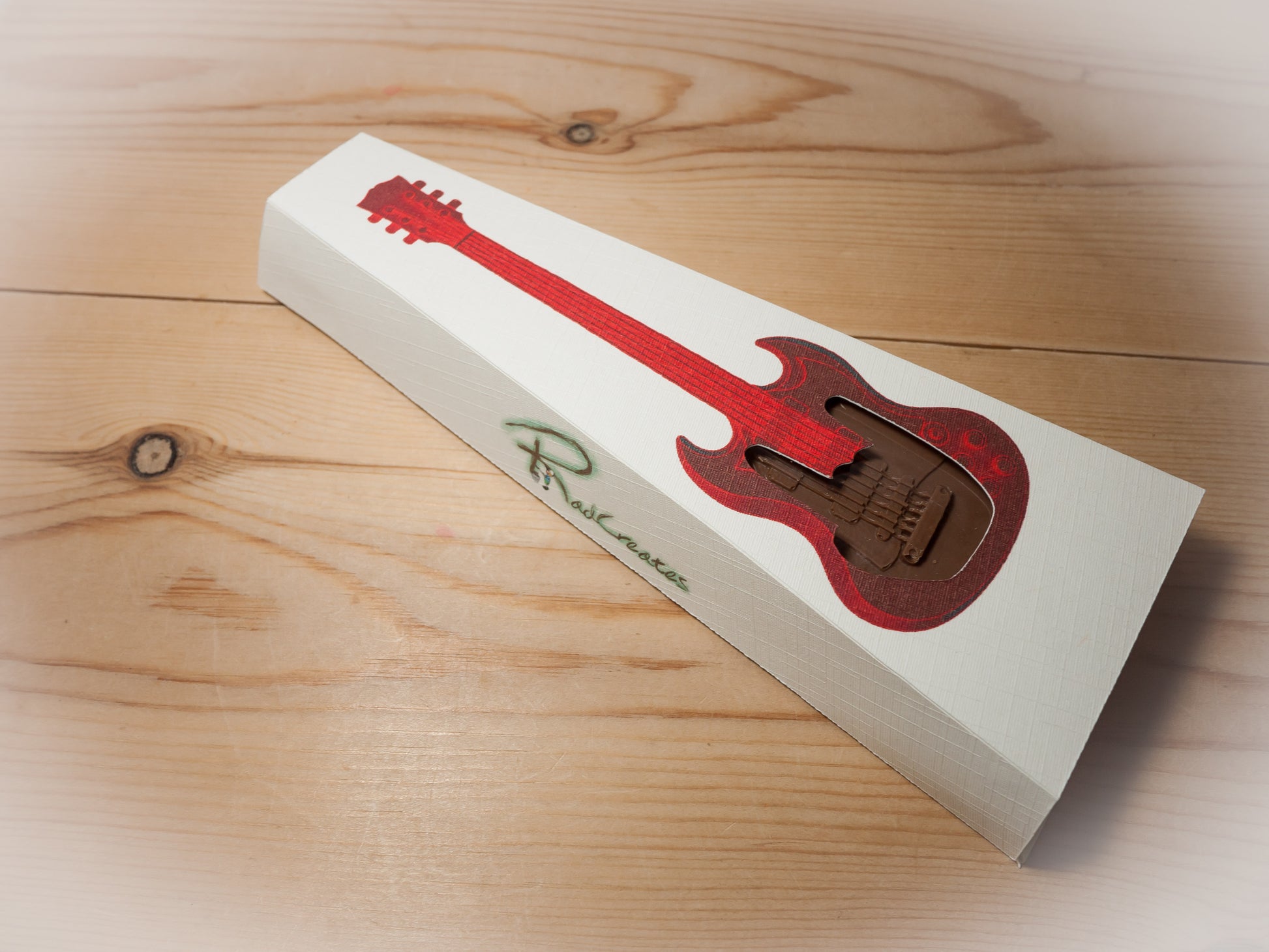 A Gibson SG guitar shaped chocolate in a gift box.