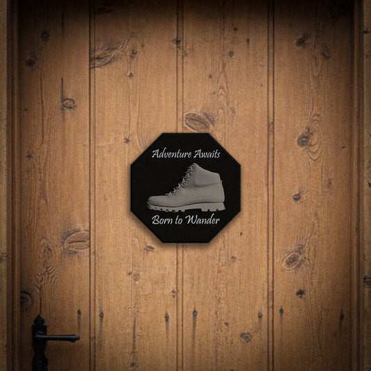 Octagonal sign with hiking boot graphic and text 'Adventure Awaits, Born to Wander' on a wooden door.