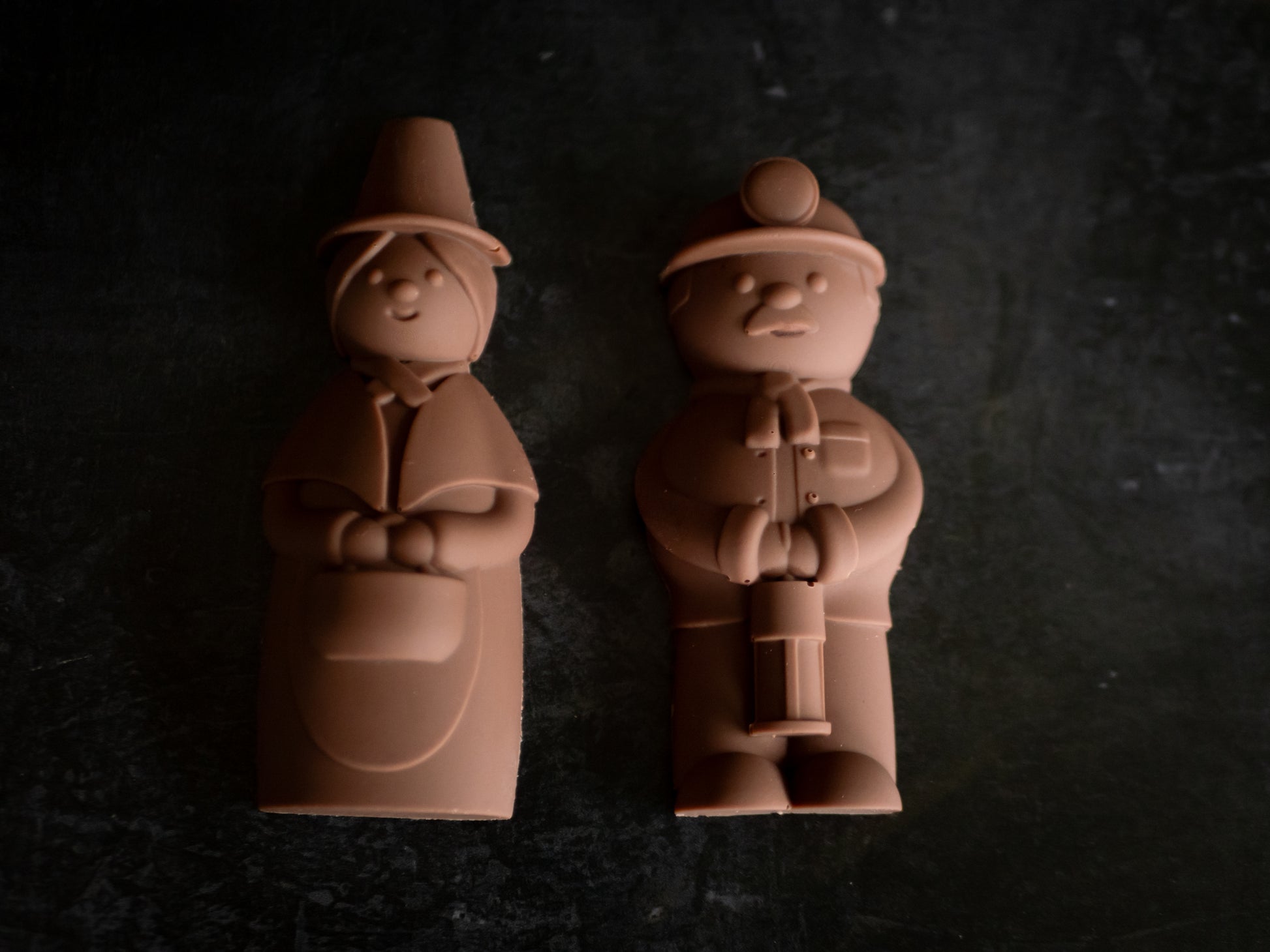 Two chocolate figures of a man and a woman on a dark surface